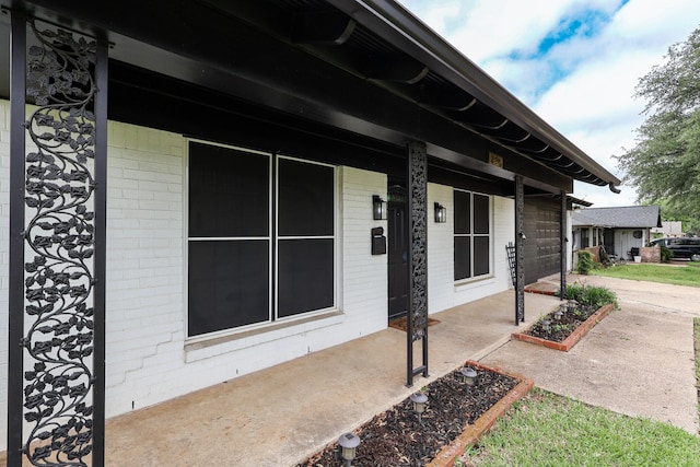 doorway to property with brick siding and a porch