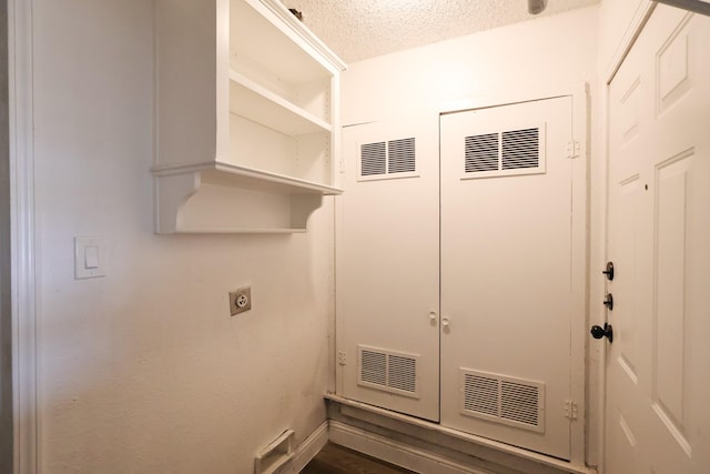 clothes washing area with electric dryer hookup and a textured ceiling