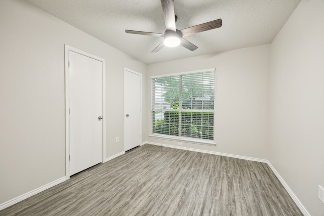 549 Seminole Trl, Murphy, TX 75094 - unfurnished bedroom featuring wood finished floors, a textured ceiling, baseboards, and a ceiling fan