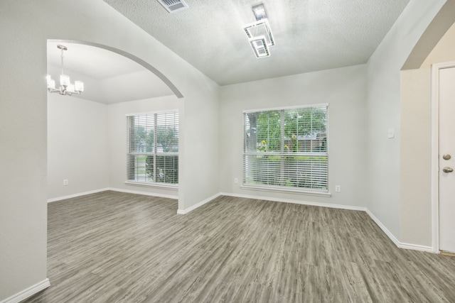 549 Seminole Trl, Murphy, TX 75094 - unfurnished room featuring wood finished floors, arched walkways, baseboards, a chandelier, and a textured ceiling