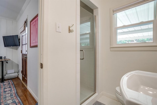 full bathroom featuring a shower stall, wood finished floors, toilet, and baseboards
