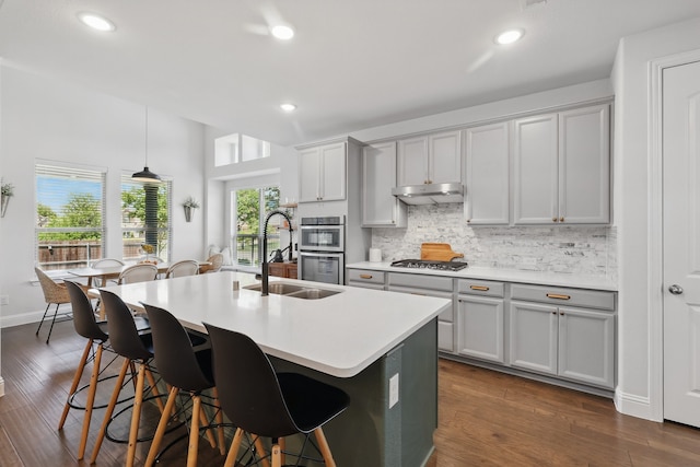 kitchen with under cabinet range hood, a sink, gray cabinets, stainless steel appliances, and recessed lighting