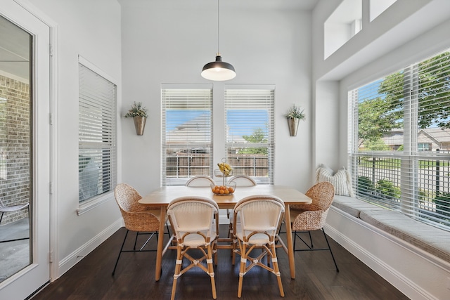 dining area featuring baseboards, dark wood-style flooring, and a towering ceiling