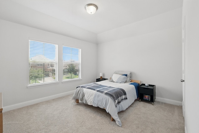 bedroom with baseboards, light colored carpet, and lofted ceiling