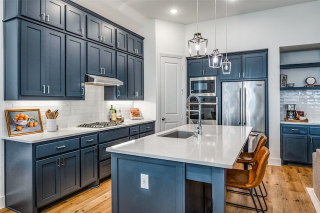 1905 Halkin Rd, Celina, TX 75009 - kitchen with stainless steel appliances, under cabinet range hood, light wood finished floors, backsplash, and decorative light fixtures
