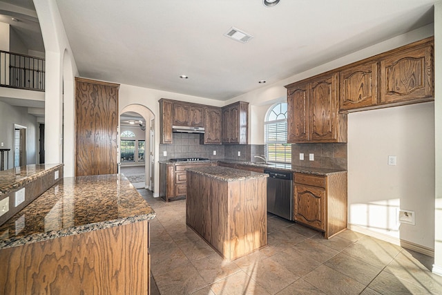 1432 Fence Post Dr, Fort Worth, TX 76052 - kitchen with stainless steel dishwasher, a kitchen island, arched walkways, decorative backsplash, and gas cooktop