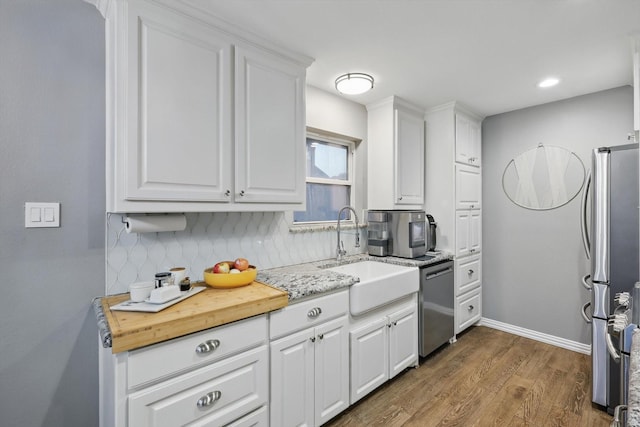 104 Radecke Rd, Krum, TX 76249 - kitchen featuring stainless steel dishwasher, a sink, wood finished floors, backsplash, and white cabinets