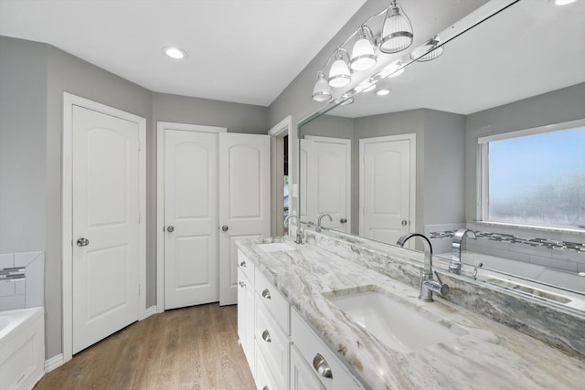 104 Radecke Rd, Krum, TX 76249 - bathroom featuring a bath, wood finished floors, double vanity, and recessed lighting