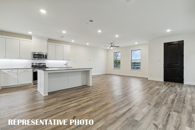 kitchen featuring stainless steel appliances, recessed lighting, a sink, light wood-style flooring, and white cabinets