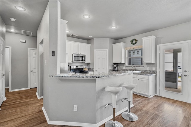 1505 Oakcrest Dr, Providence Village, TX 76227 - kitchen with appliances with stainless steel finishes, light wood-style floors, white cabinets, and recessed lighting