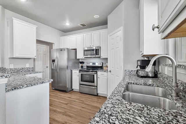 1505 Oakcrest Dr, Providence Village, TX 76227 - kitchen with stainless steel appliances, a sink, light wood finished floors, white cabinets, and recessed lighting