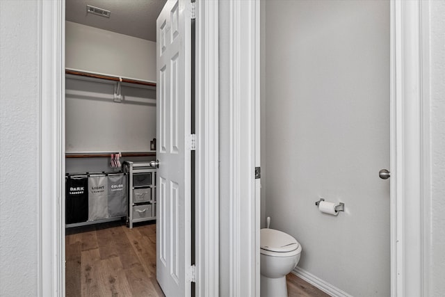 1505 Oakcrest Dr, Providence Village, TX 76227 - bathroom featuring wood finished floors, toilet, a spacious closet, and baseboards