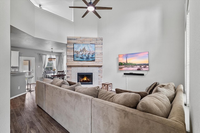 1505 Oakcrest Dr, Providence Village, TX 76227 - living room with a ceiling fan, dark wood-type flooring, a towering ceiling, baseboards, and a tiled fireplace