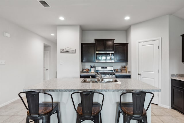 16417 Marinette Ct, Justin, TX 76247 - kitchen featuring stainless steel appliances, a breakfast bar area, light tile patterned floors, an island with sink, and recessed lighting