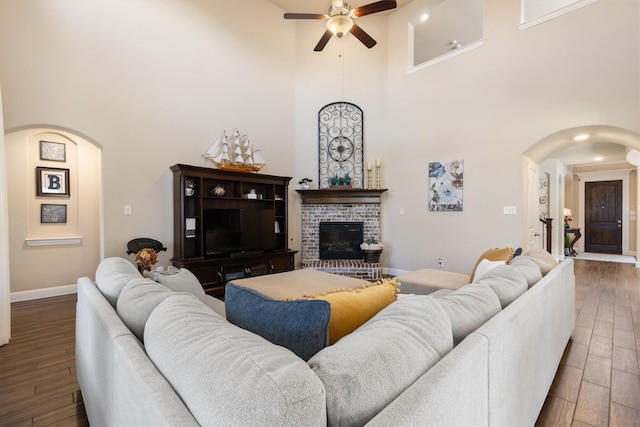 102 Autumn Sage Dr, Wylie, TX 75098 - living room with arched walkways, a ceiling fan, a high ceiling, wood finished floors, and a brick fireplace