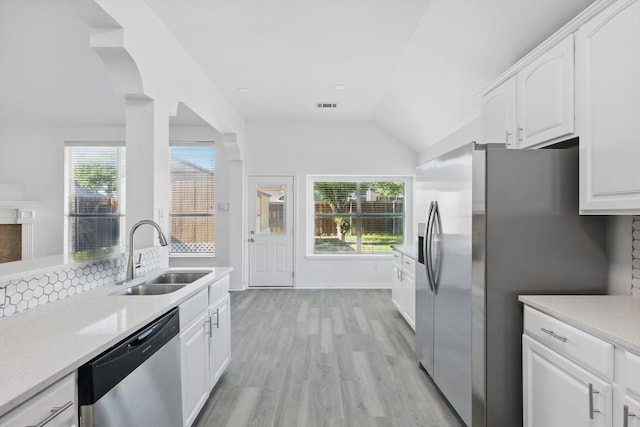 1228 Carriage Creek Dr, Desoto, TX 75115 - kitchen with a sink, stainless steel appliances, light wood finished floors, vaulted ceiling, and white cabinetry