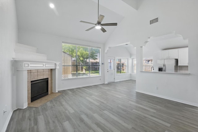 1228 Carriage Creek Dr, Desoto, TX 75115 - unfurnished living room with high vaulted ceiling, ceiling fan, wood finished floors, a tiled fireplace, and baseboards