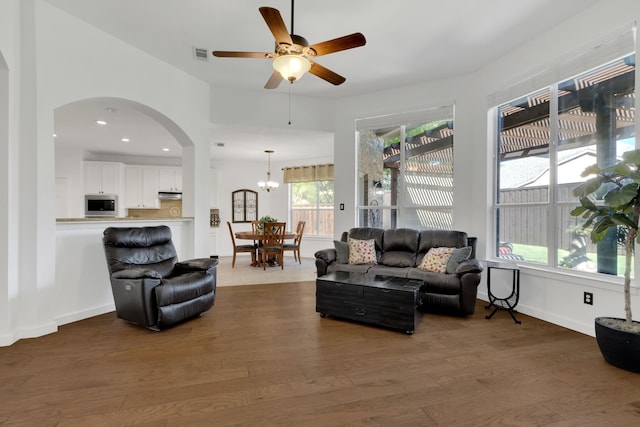 living room featuring arched walkways, ceiling fan, dark wood-style flooring, a chandelier, and recessed lighting