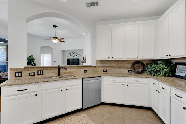 kitchen with stainless steel dishwasher, arched walkways, a sink, decorative backsplash, and white cabinets
