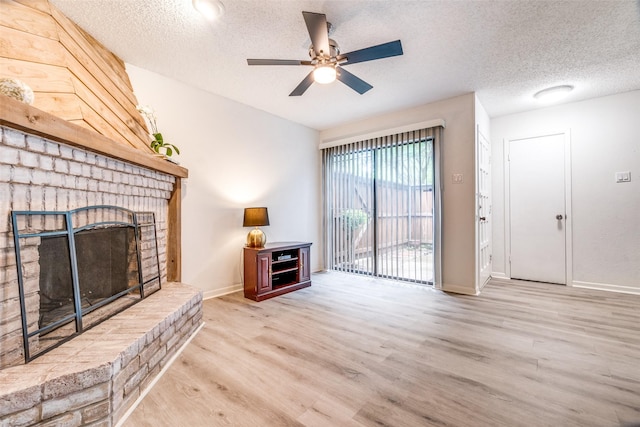 unfurnished living room with a brick fireplace, wood finished floors, a textured ceiling, ceiling fan, and baseboards