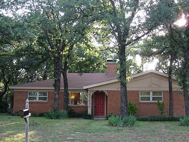 ranch-style home featuring a front lawn, a chimney, and brick siding