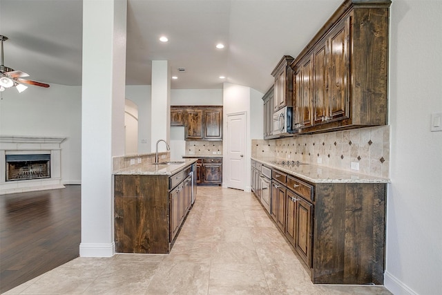 5232 Buffalo Gap Trl, Fort Worth, TX 76126 - kitchen featuring a sink, stainless steel microwave, a ceiling fan, light stone counters, and dark brown cabinetry