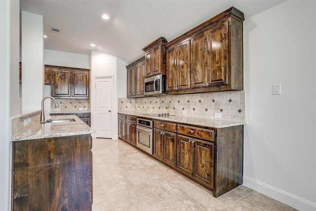5232 Buffalo Gap Trl, Fort Worth, TX 76126 - kitchen featuring appliances with stainless steel finishes, a sink, light stone countertops, dark brown cabinets, and tasteful backsplash