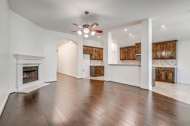5232 Buffalo Gap Trl, Fort Worth, TX 76126 - unfurnished living room featuring ceiling fan, arched walkways, wood finished floors, a fireplace with raised hearth, and baseboards