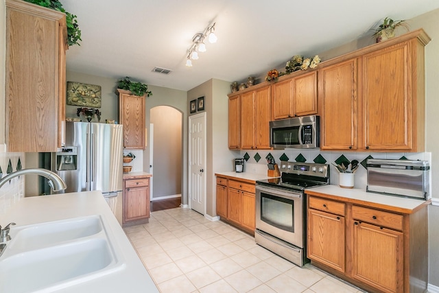 4820 Rum St, Fort Worth, TX 76244 - kitchen featuring appliances with stainless steel finishes, a sink, arched walkways, and light countertops