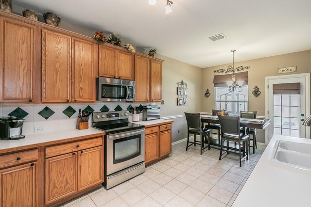 4820 Rum St, Fort Worth, TX 76244 - kitchen featuring appliances with stainless steel finishes, brown cabinetry, a sink, and backsplash