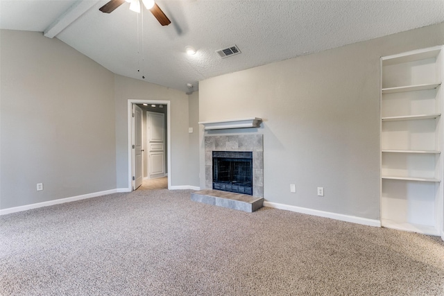 unfurnished living room with carpet flooring, ceiling fan, a tiled fireplace, and baseboards