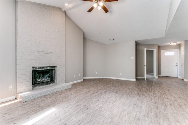 unfurnished living room featuring ceiling fan, wood finished floors, a brick fireplace, vaulted ceiling, and baseboards