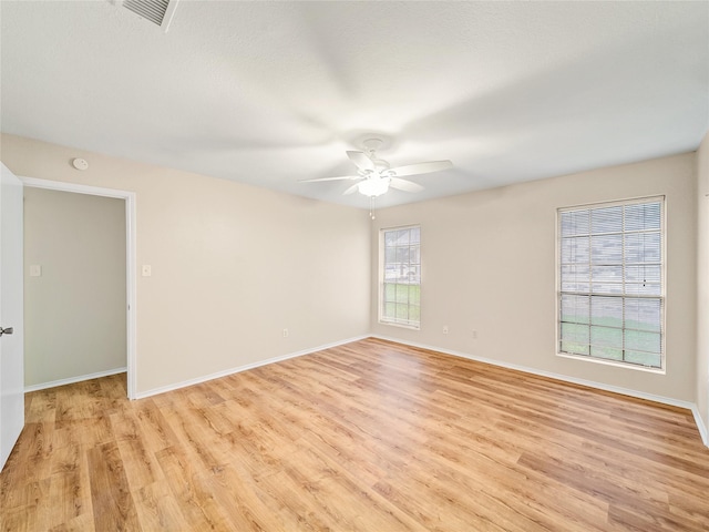 spare room with light wood-style floors, ceiling fan, and baseboards