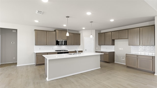 1700 Elle Ln, Aubrey, TX 76227 - kitchen with a sink, tasteful backsplash, light wood-type flooring, a kitchen island with sink, and light countertops