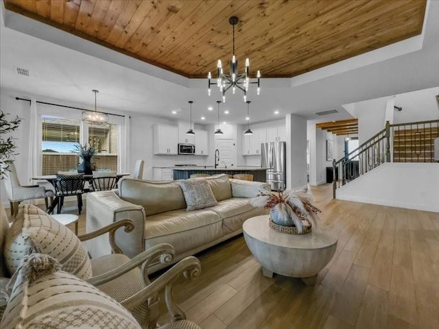 3605 Keechi Creek Dr, Celina, TX 75078 - living room featuring a chandelier, wooden ceiling, a raised ceiling, light wood-style flooring, and stairway