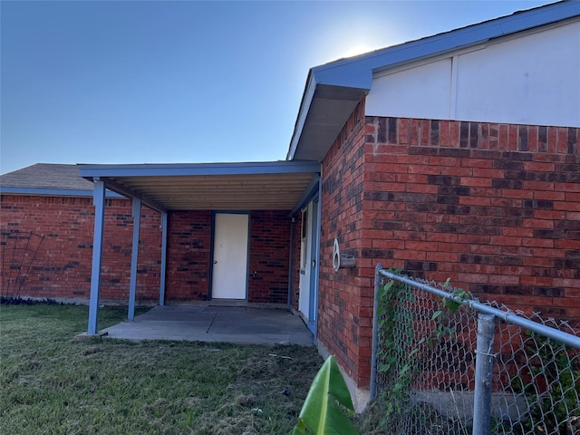entrance to property with brick siding and a patio area