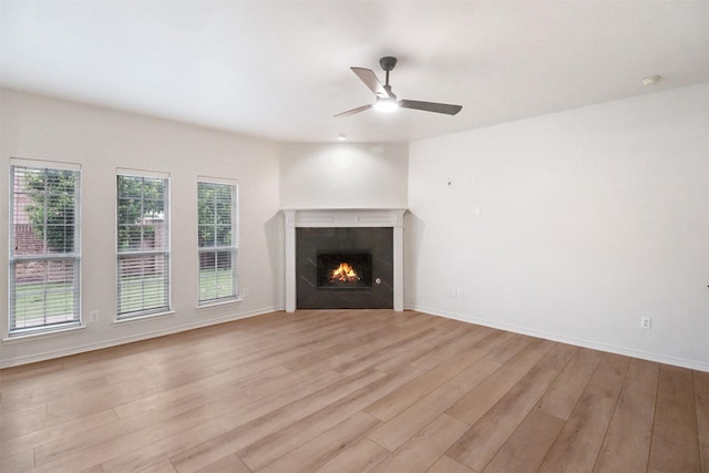 9103 Aristocrat Ln, Frisco, TX 75033 - unfurnished living room with light wood-style flooring, a ceiling fan, a warm lit fireplace, and baseboards