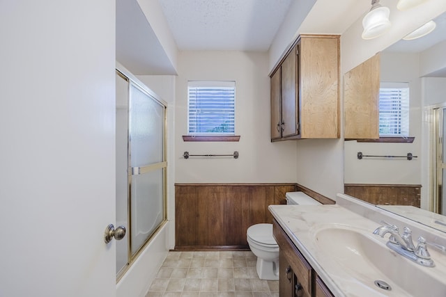 2011 Woodlawn St, Gainesville, TX 76240 - full bath featuring toilet, vanity, wainscoting, and enclosed tub / shower combo