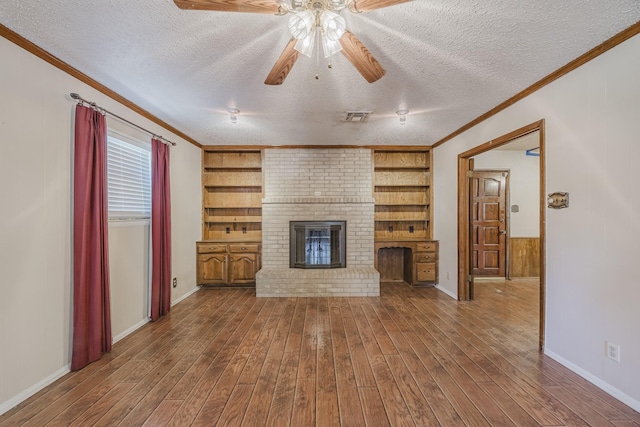 2011 Woodlawn St, Gainesville, TX 76240 - unfurnished living room featuring ceiling fan, hardwood / wood-style floors, ornamental molding, a textured ceiling, and a fireplace