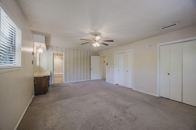 2011 Woodlawn St, Gainesville, TX 76240 - unfurnished bedroom with multiple closets, wallpapered walls, baseboards, a textured ceiling, and carpet flooring