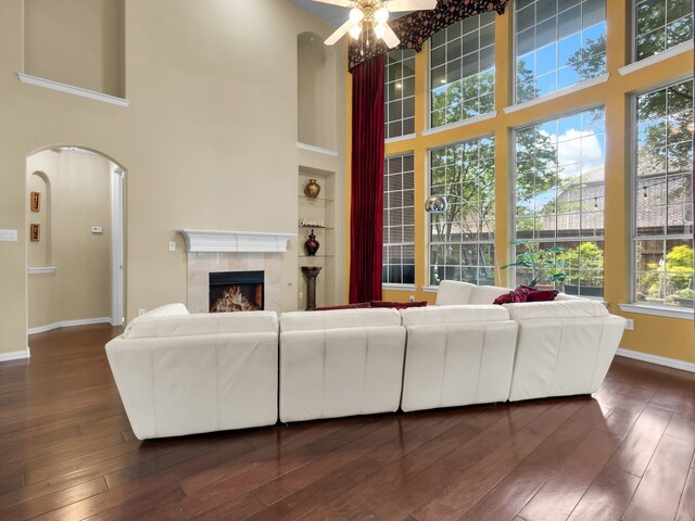 1217 Mandeville Dr, Murphy, TX 75094 - living room featuring a towering ceiling, a ceiling fan, a tile fireplace, dark wood finished floors, and baseboards