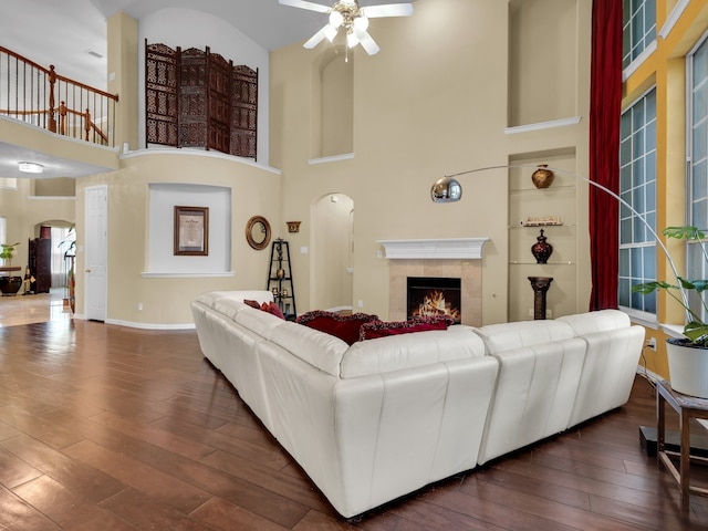 1217 Mandeville Dr, Murphy, TX 75094 - living area featuring arched walkways, ceiling fan, a high ceiling, a tiled fireplace, and hardwood / wood-style floors