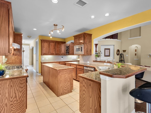 1217 Mandeville Dr, Murphy, TX 75094 - kitchen featuring arched walkways, appliances with stainless steel finishes, a sink, a peninsula, and tasteful backsplash