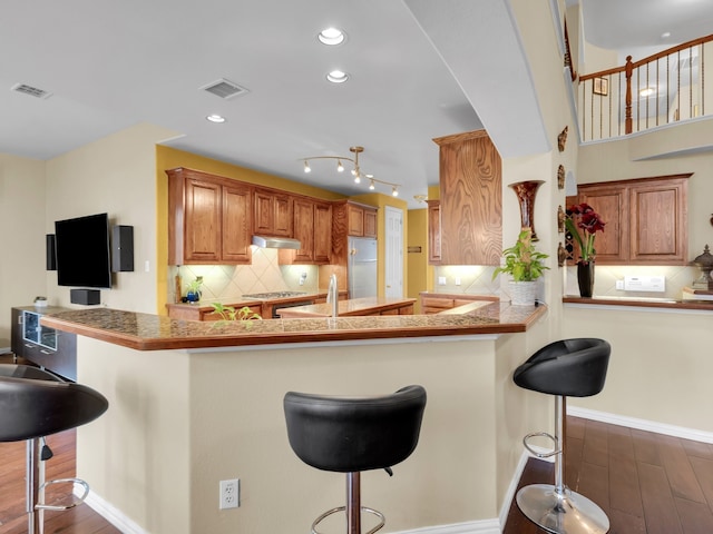 1217 Mandeville Dr, Murphy, TX 75094 - kitchen with dark wood-style flooring, a kitchen breakfast bar, under cabinet range hood, appliances with stainless steel finishes, and recessed lighting