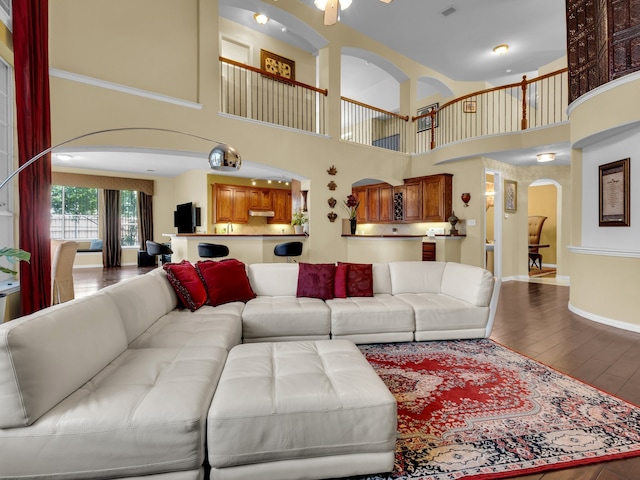1217 Mandeville Dr, Murphy, TX 75094 - living room with arched walkways, hardwood / wood-style flooring, a towering ceiling, ceiling fan, and baseboards