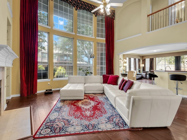 1217 Mandeville Dr, Murphy, TX 75094 - living room featuring a towering ceiling, hardwood / wood-style flooring, a ceiling fan, a tiled fireplace, and arched walkways