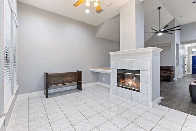 7601 Silverthorn, Rowlett, TX 75089 - unfurnished living room featuring a ceiling fan, high vaulted ceiling, a tiled fireplace, baseboards, and tile patterned floors