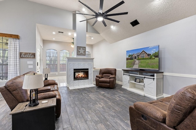 7601 Silverthorn, Rowlett, TX 75089 - living area featuring ceiling fan, dark wood finished floors, a tiled fireplace, high vaulted ceiling, and baseboards