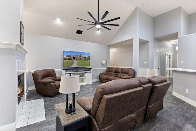 7601 Silverthorn, Rowlett, TX 75089 - living area featuring a ceiling fan, high vaulted ceiling, a tile fireplace, baseboards, and dark wood-type flooring
