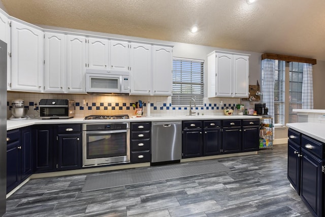 7601 Silverthorn, Rowlett, TX 75089 - kitchen with appliances with stainless steel finishes, a sink, white cabinets, dark cabinetry, and a textured ceiling